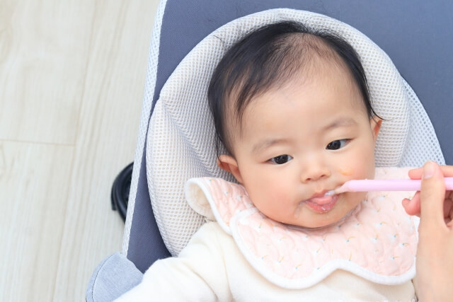 よだれかけをして離乳食を食べる